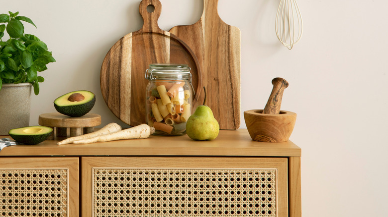 An assortment of kitchen items placed on a rattan cabinet