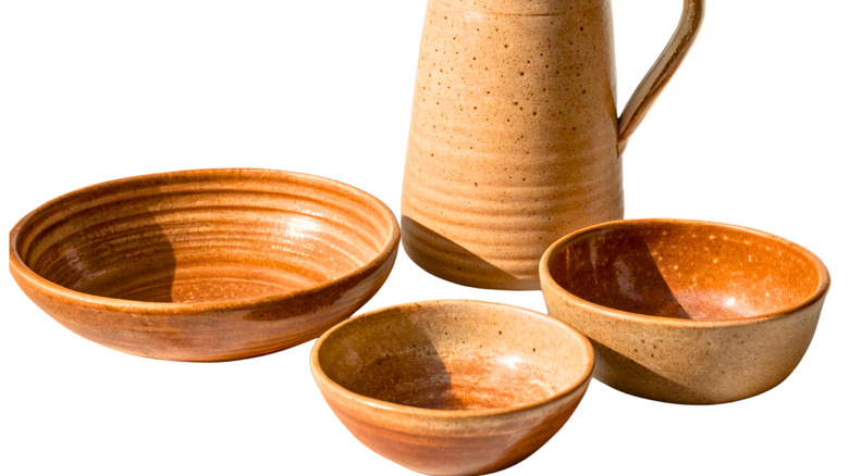 Several terracotta bowls and pitcher against an isolated while background