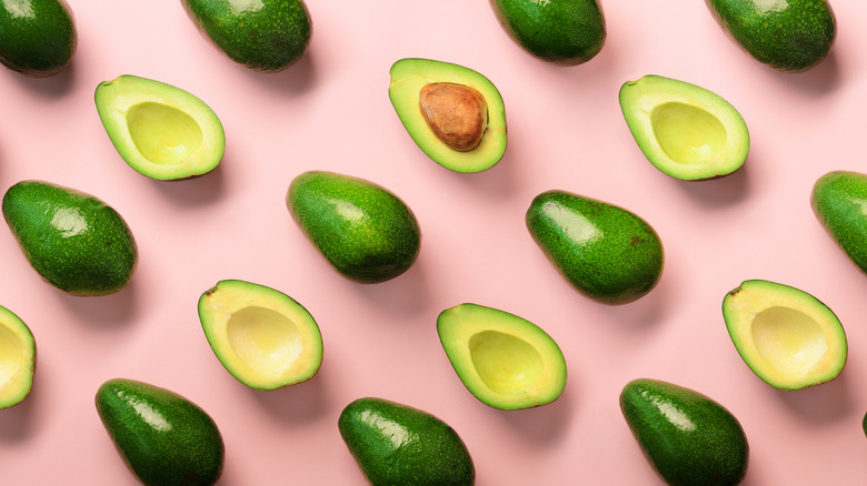 Halved avocados on a pink background