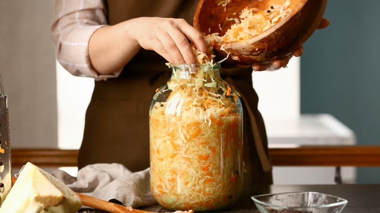 Woman putting sauerkraut in glass jar