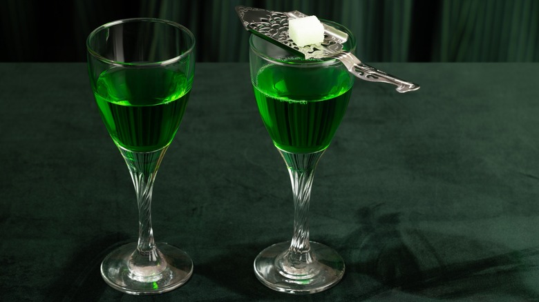 Two glasses of green absinthe with a silver spoon and sugar cube