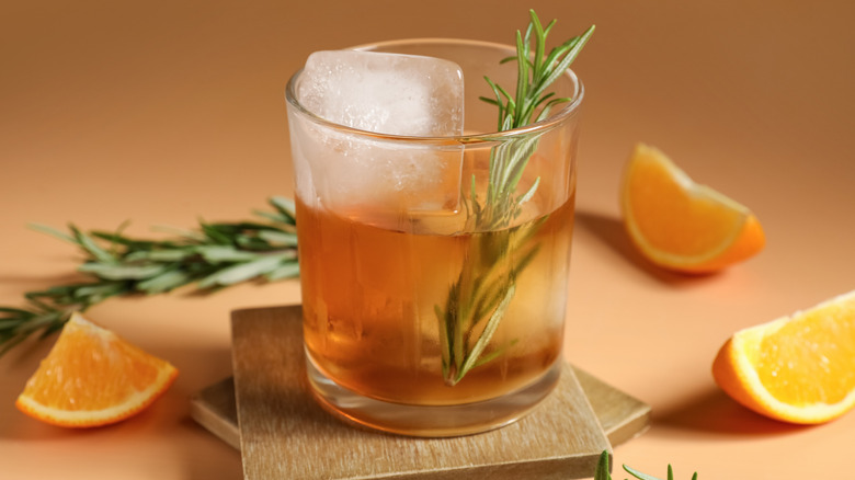 Old fashioned cocktail with orange slices, rosemary