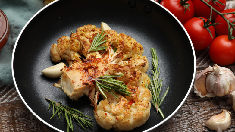 cauliflower steak in a pan with garlic & rosemary