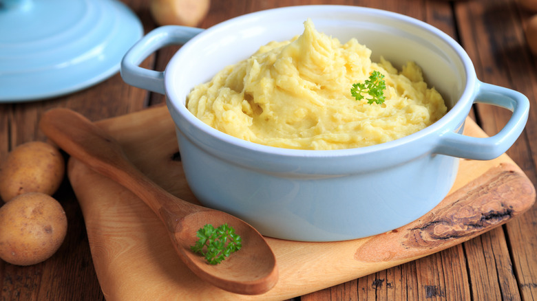 Crock of mashed potatoes with wooden spoon