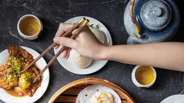 hand using chopsticks on dim sum