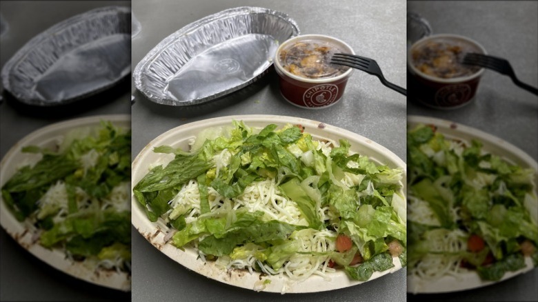 A Chipotle burrito bowl beside a cup of extra chicken.