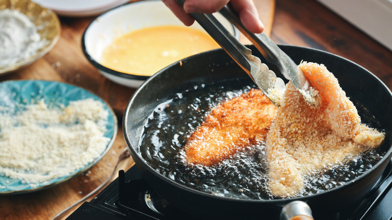 Person frying chicken cutlets with a panko crust.