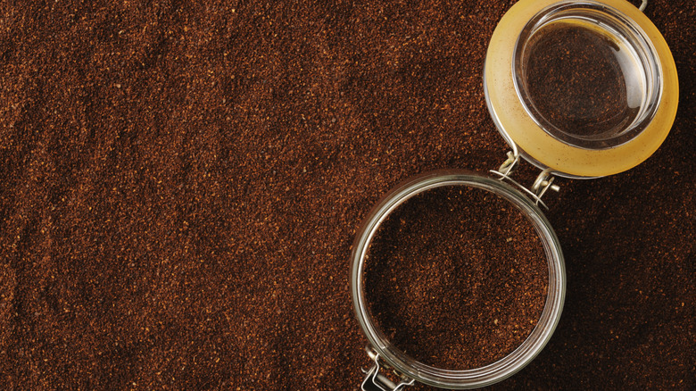 a sealable jar full of coffee grounds sitting in more coffee grounds