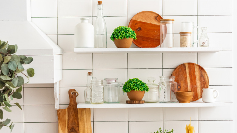 Kitchen open shelves with plants, bottles, bread boards
