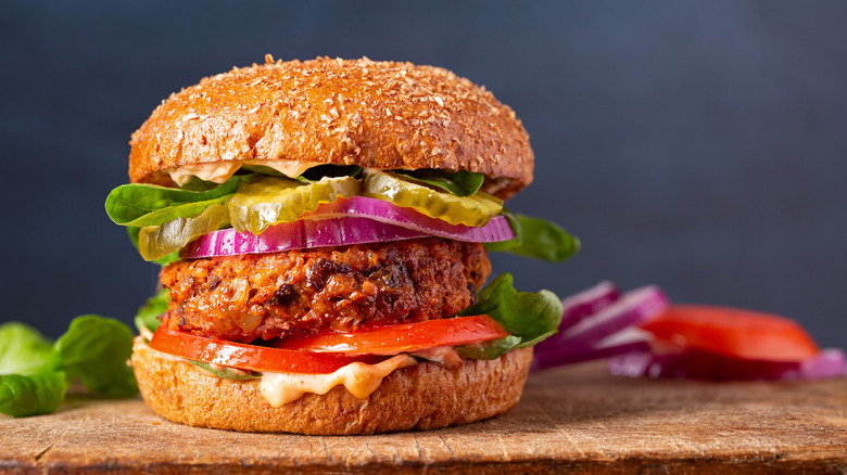 A stacked veggie burger with tomatoes, pickles, and onions.