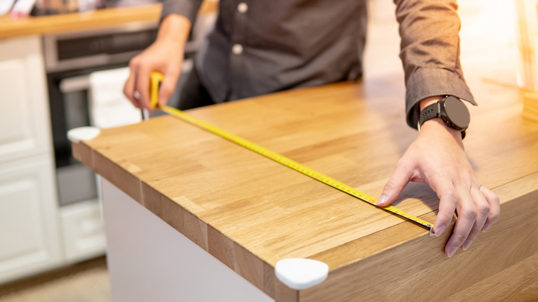 Man measuring wooden kitchen countertop