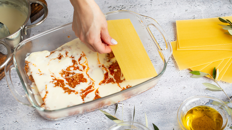 A person assembling layers of lasagna in their kitchen
