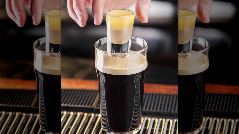 Hand dropping shot into dark beer on bar