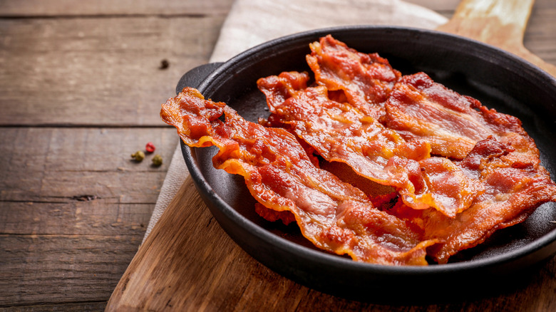 A cast iron skillet with strips of bacon in it