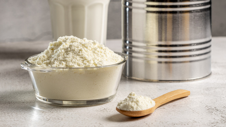 small bowl of powdered milk next to a glass of milk and can