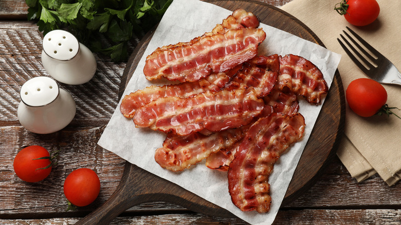 board of crispy bacon with tomatoes and salt and pepper shaker