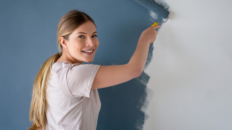 A woman painting a wall dark blue