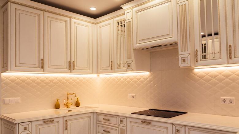 A ktichen with under-cabinet lighting beneath white cabinets