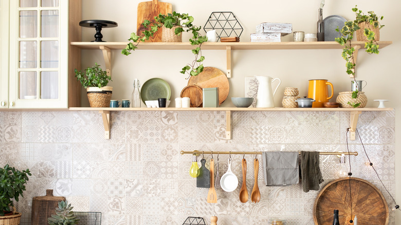 Open shelves in a kitchen with various vases, plants, and cutting board decor