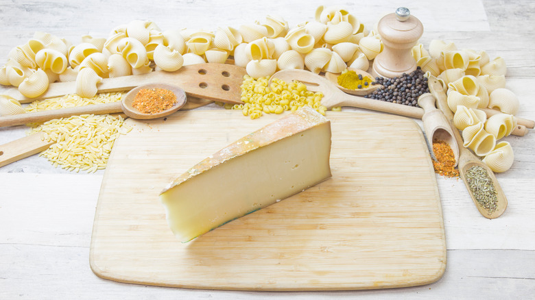 Fontina cheese on wooden board with utensils