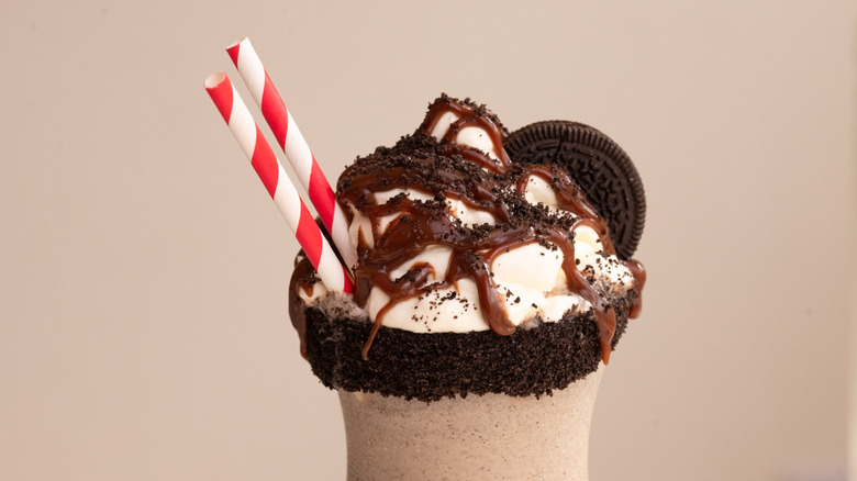 Oreo milkshake with straws, chocolate drizzle, and cookie crumbs
