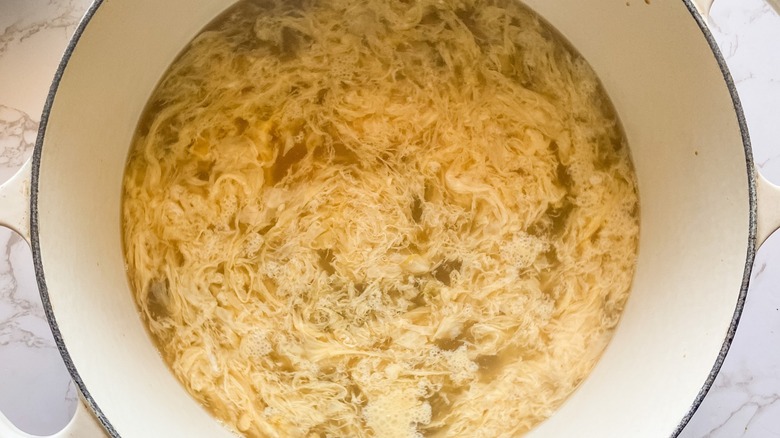 Top-down view of egg drop soup in a white pot