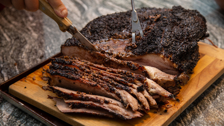 Someone cutting smoked brisket