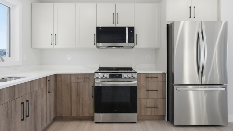 Kitchen with white upper cabinets and darker, wooden lower cabinets.