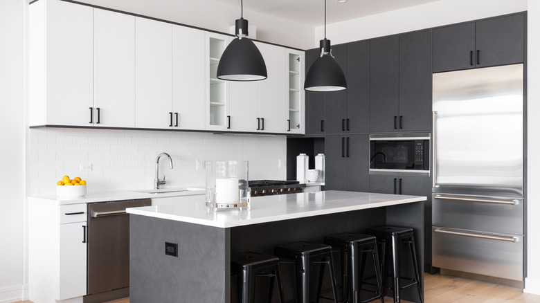 A black and white kitchen with cabinets in both tones and an island in the center.