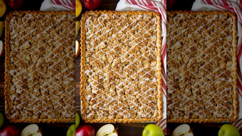 An apple slab pie on a cutting board, various apples at the base