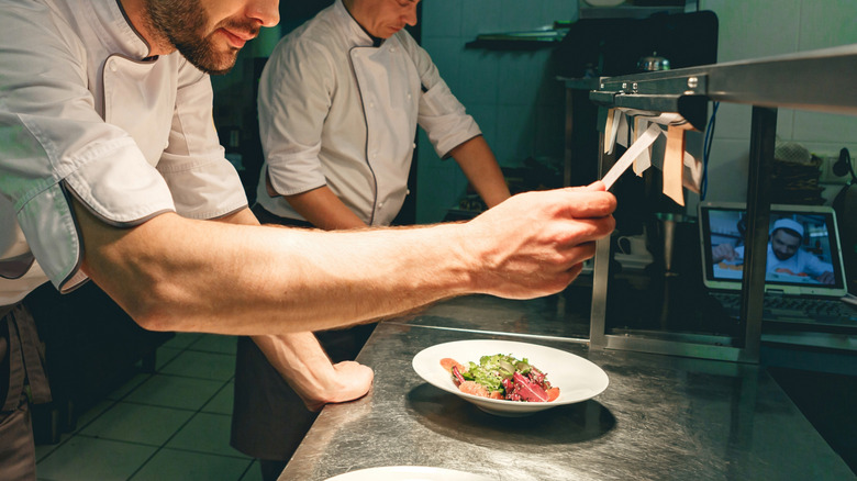 a chef reads an order ticket at the pass