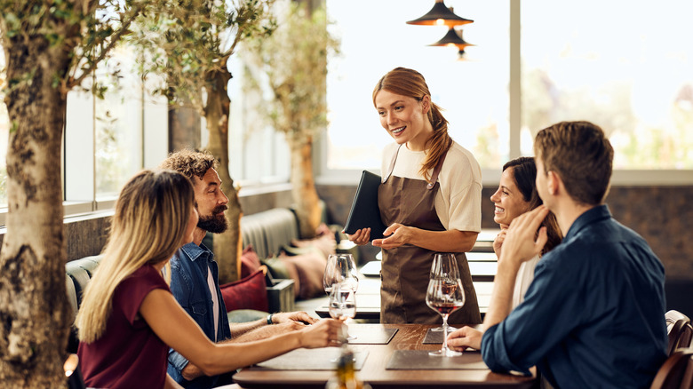 a server speaks to a table of four diners