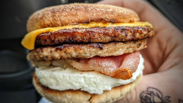 man holding stacked breakfast sandwich