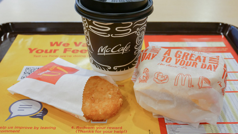 McDonald's tray containing a cup of coffee, hash brown, and wrapped sandwich.