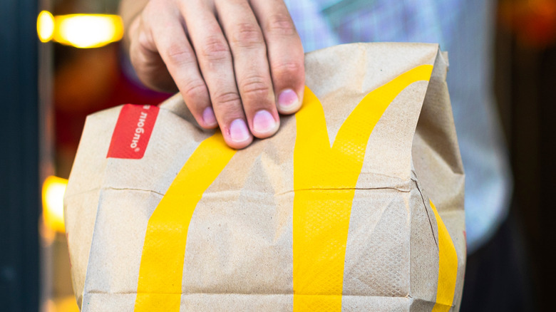 A person's hand holding a McDonald's bag.