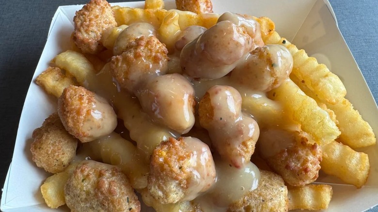 A Culver's boat with fries, cheese curds, and light brown chicken gravy sits on a table.