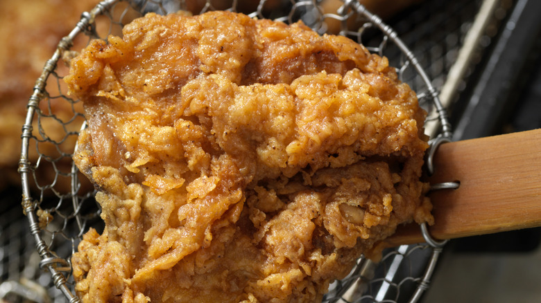 chicken being pulled out of a fryer