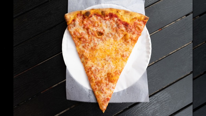 Slice of cheese pizza on paper plate with wax paper