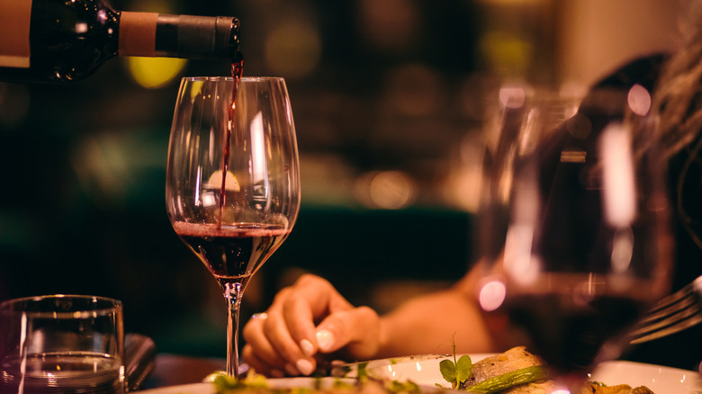 Close-up of a server pouring wine tableside at a restaurant