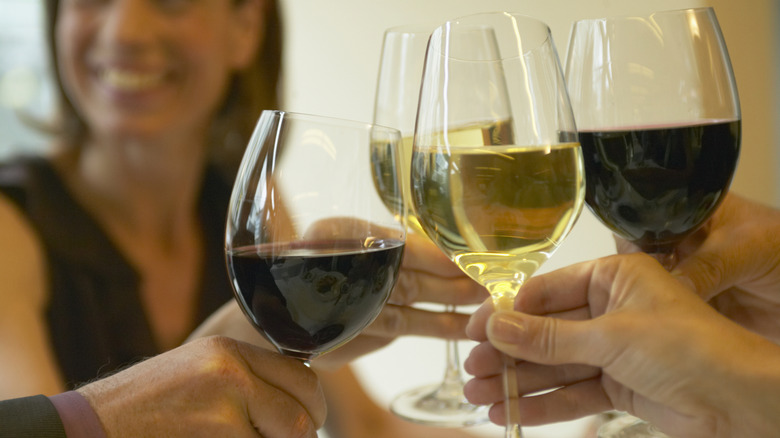 Dining companions cheersing different types of wine in long-stemmed glasses