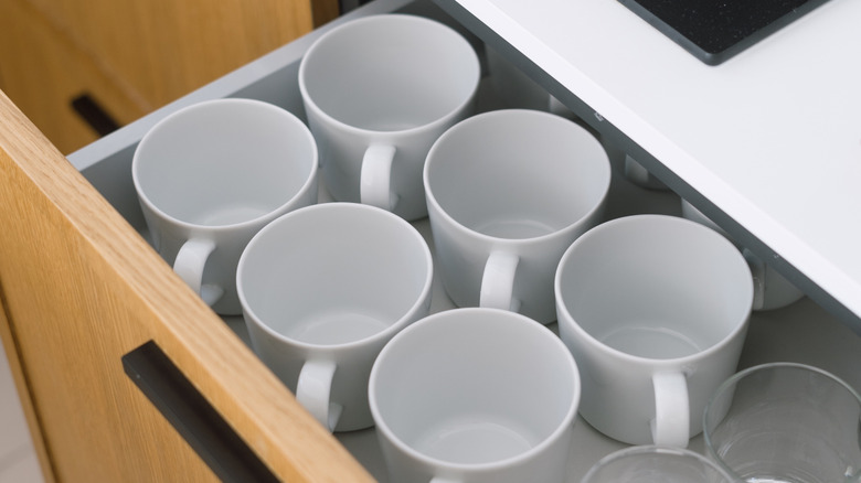Mugs standing upright in a kitchen drawer