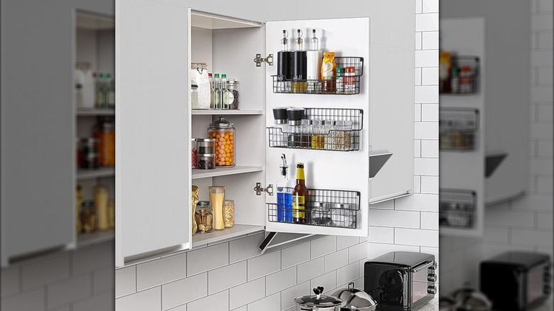 Hand opening a cupboard to show white mugs inside
