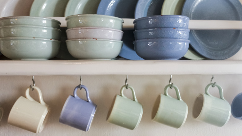 Mugs displayed on mug hooks underneath matching dishes
