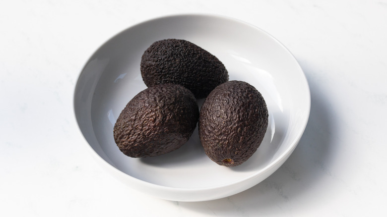 Three avocados in white bowl