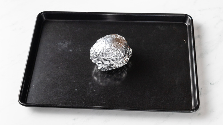 Foil-wrapped avocado on baking sheet