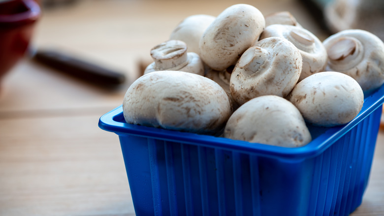 A blue container of white button mushrooms