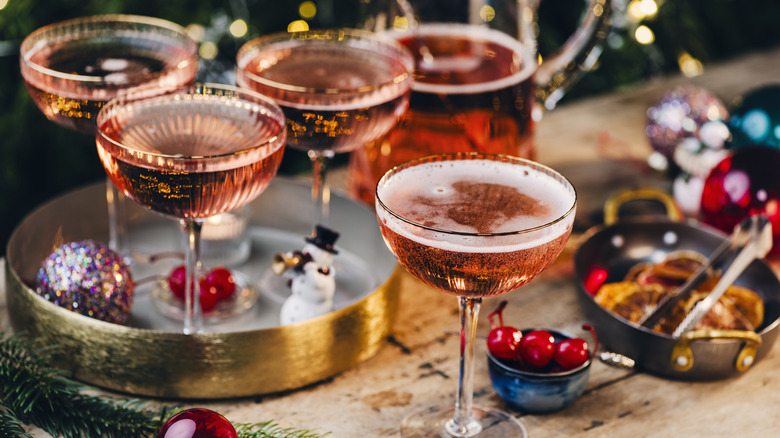 A Christmas-themed bar cart with red martinis, decorations and garnishes.