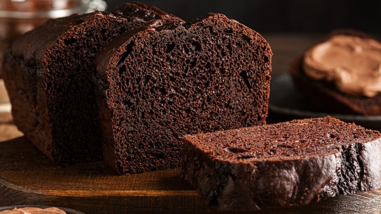 A sliced chocolate pound cake on a wooden board