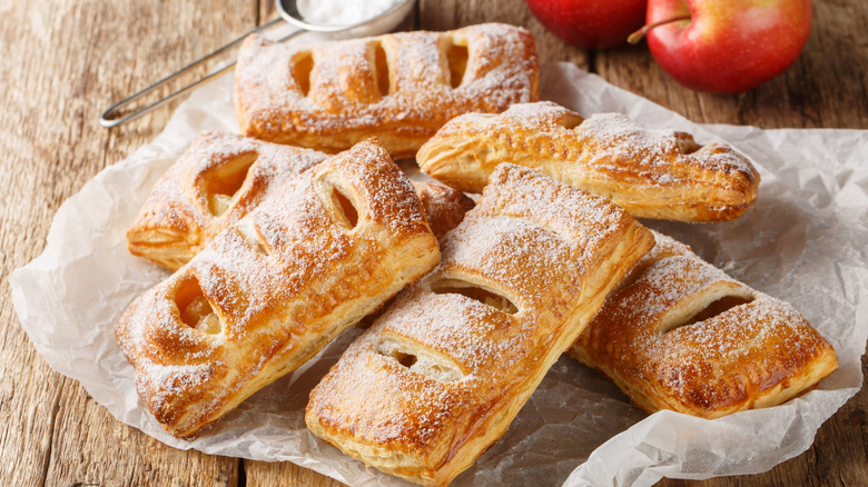 Closeup view of fresh puff pastry apple turnovers on parchment paper