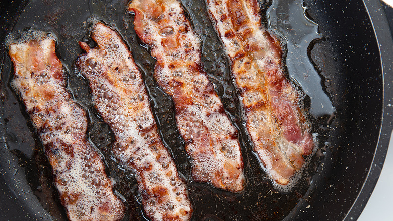 Bacon strips with fat in a pan